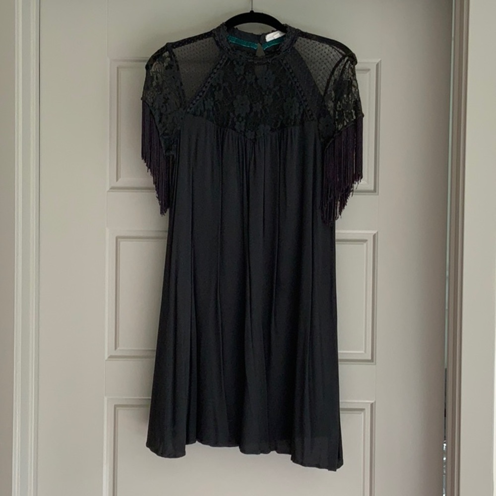 Black dress with lace top and fringe sleeves.
